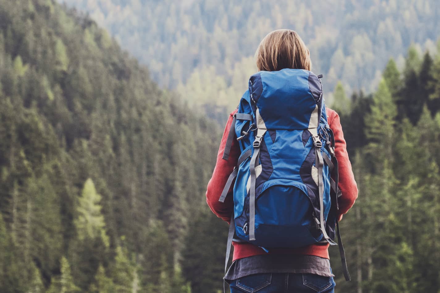 Woman with a blue lightweight backpack and what appears to be a manageable base weight to hike longer distances with more comfort.