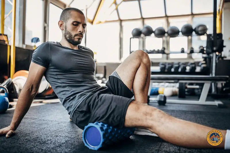 Man in the gym using a foam roller on his leg