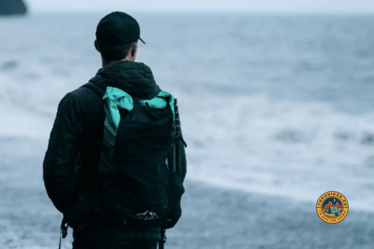 Man hiking on the beach with a Robic green ULA Photon backpack
